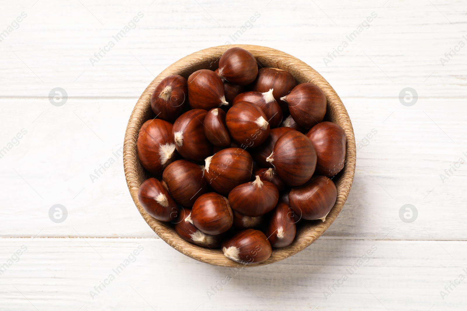 Photo of Fresh sweet edible chestnuts on white wooden table, top view
