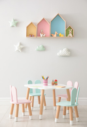 House shaped shelves and little table with chairs in children's room. Interior design