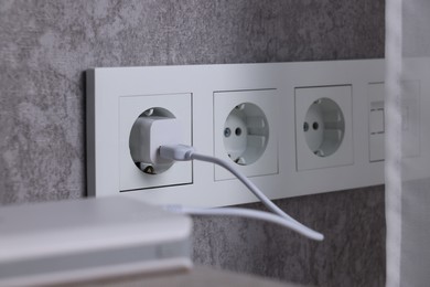 Photo of Power bank plugged into electric socket on grey wall