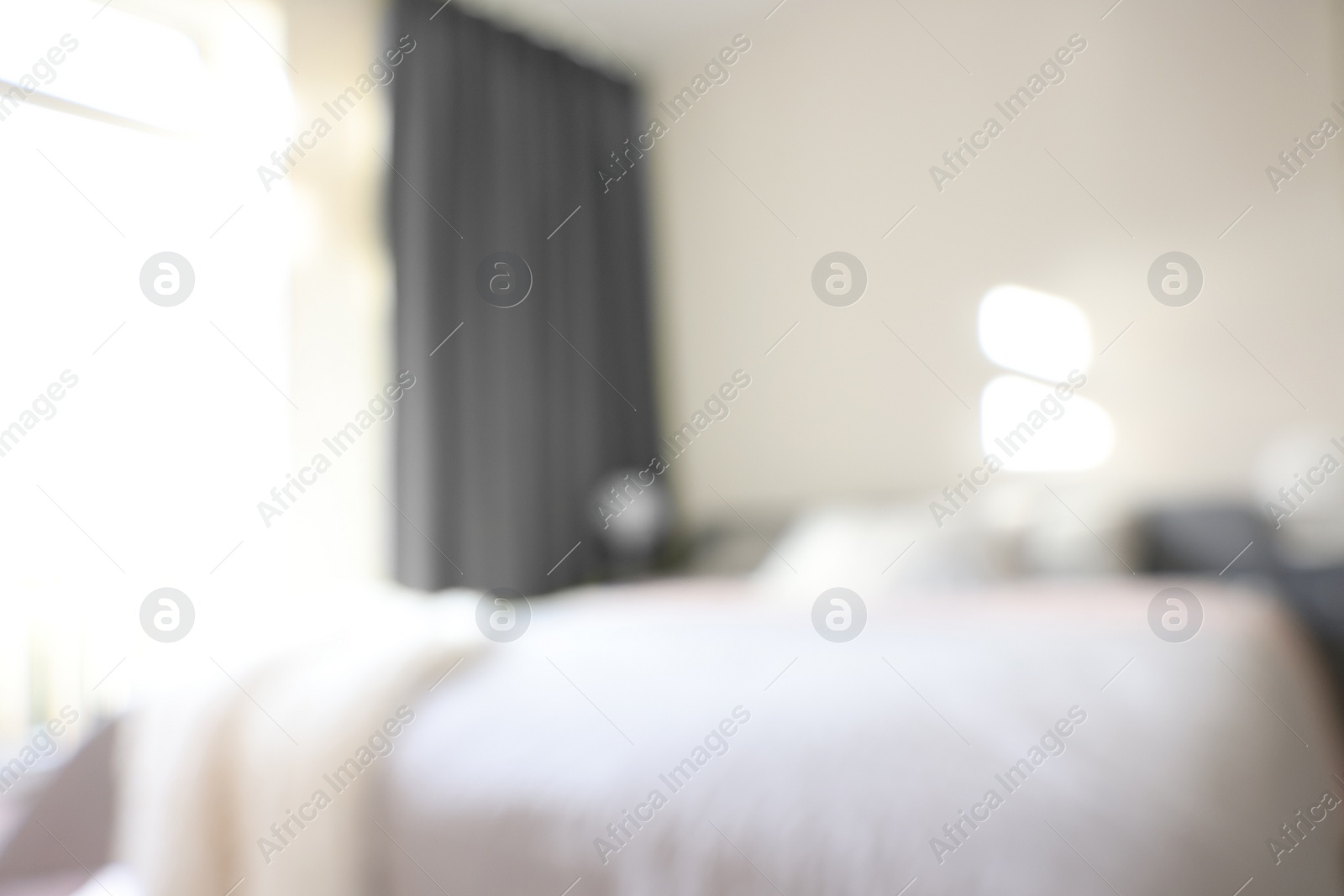 Photo of Blurred view of large bed near window in room