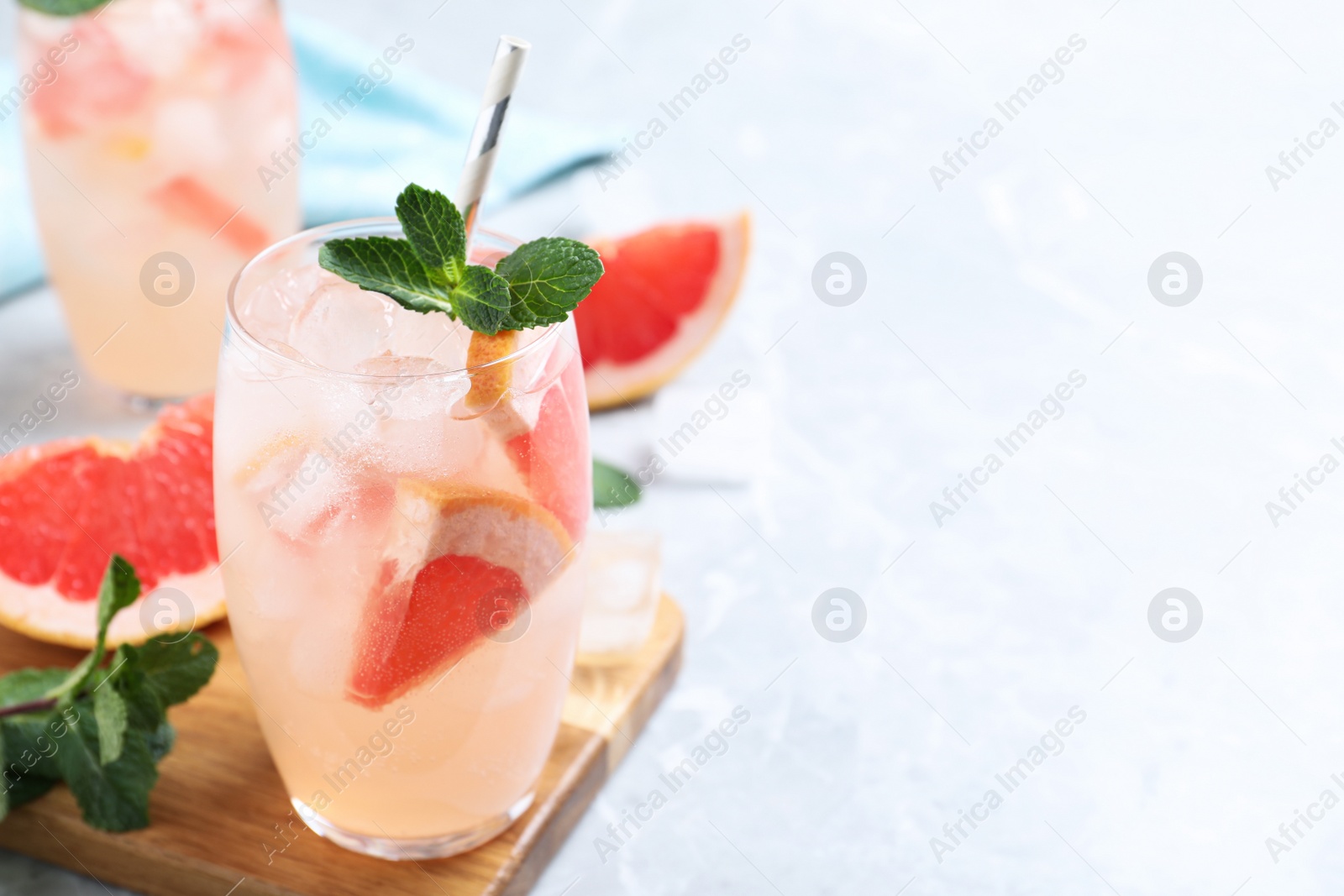 Photo of Glass of fresh cocktail with grapefruit on light marble table. Space for text