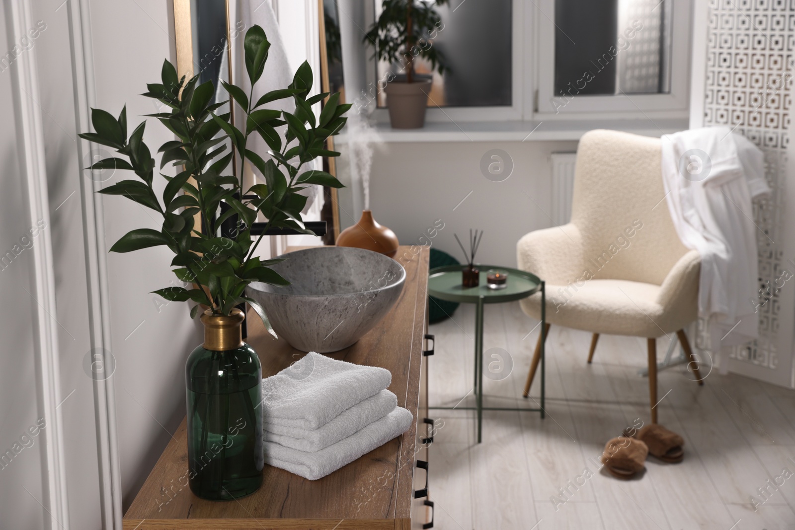 Photo of Modern bathroom interior with stylish mirror, eucalyptus branches, vessel sink and wooden vanity