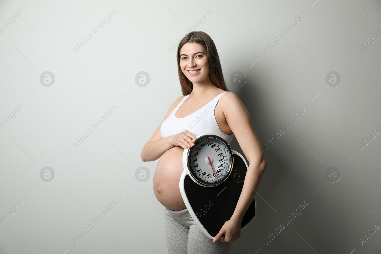 Photo of Pregnant woman with scales on grey background