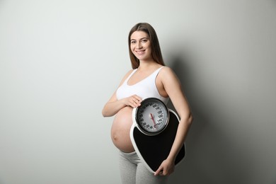 Photo of Pregnant woman with scales on grey background