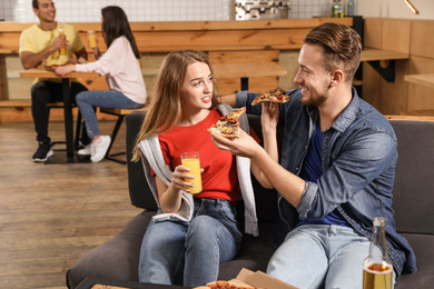 Photo of Young couple eating delicious pizza in cafe