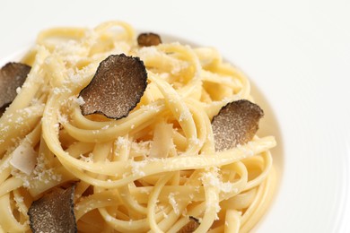 Photo of Delicious pasta with truffle slices and cheese on plate, closeup