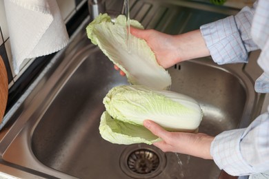 Photo of Woman washing fresh Chinese cabbage in sink, closeup