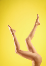 Photo of Woman wearing tights on yellow background, closeup of legs