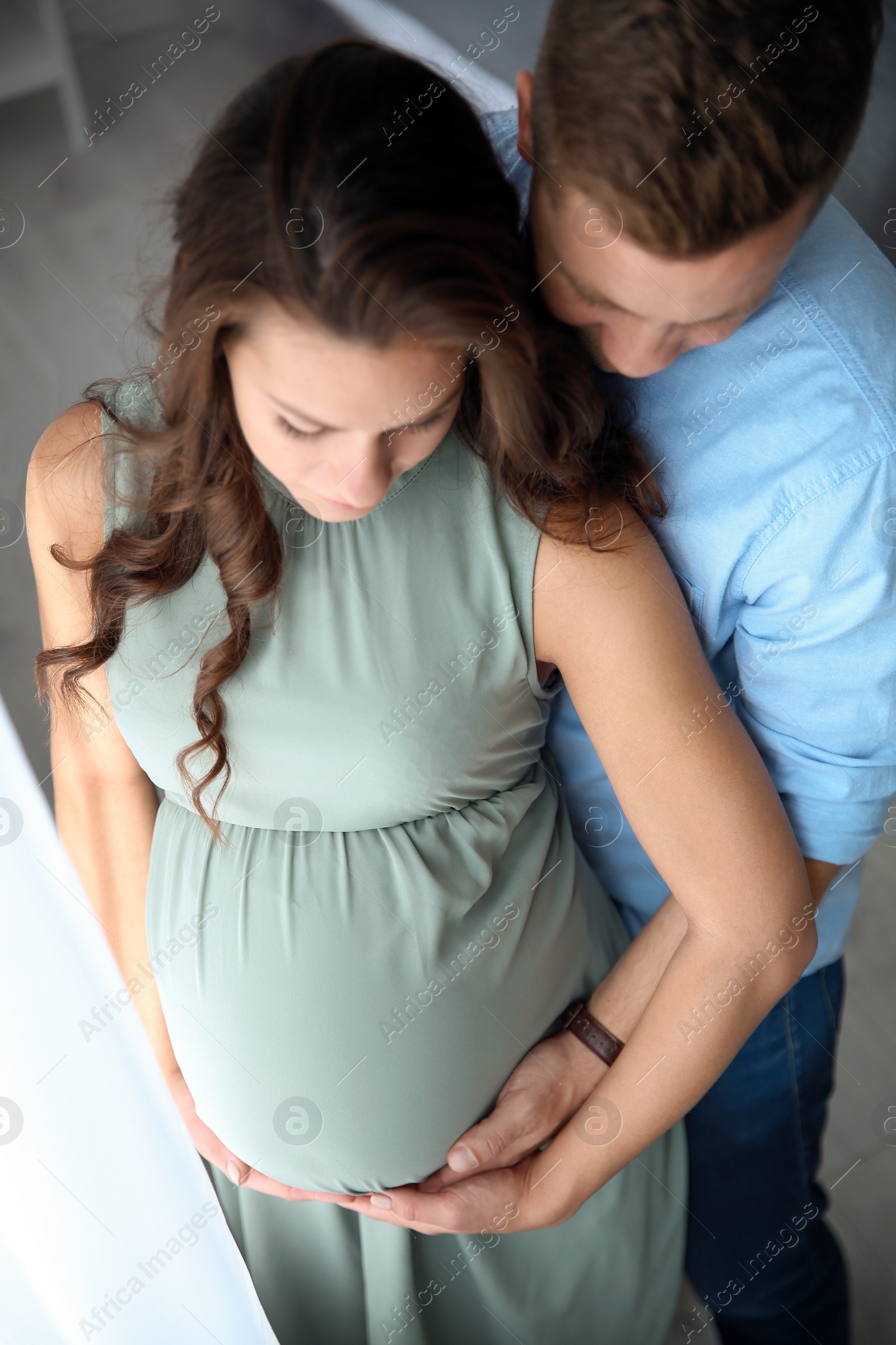 Photo of Pregnant woman with her husband indoors. Happy young family