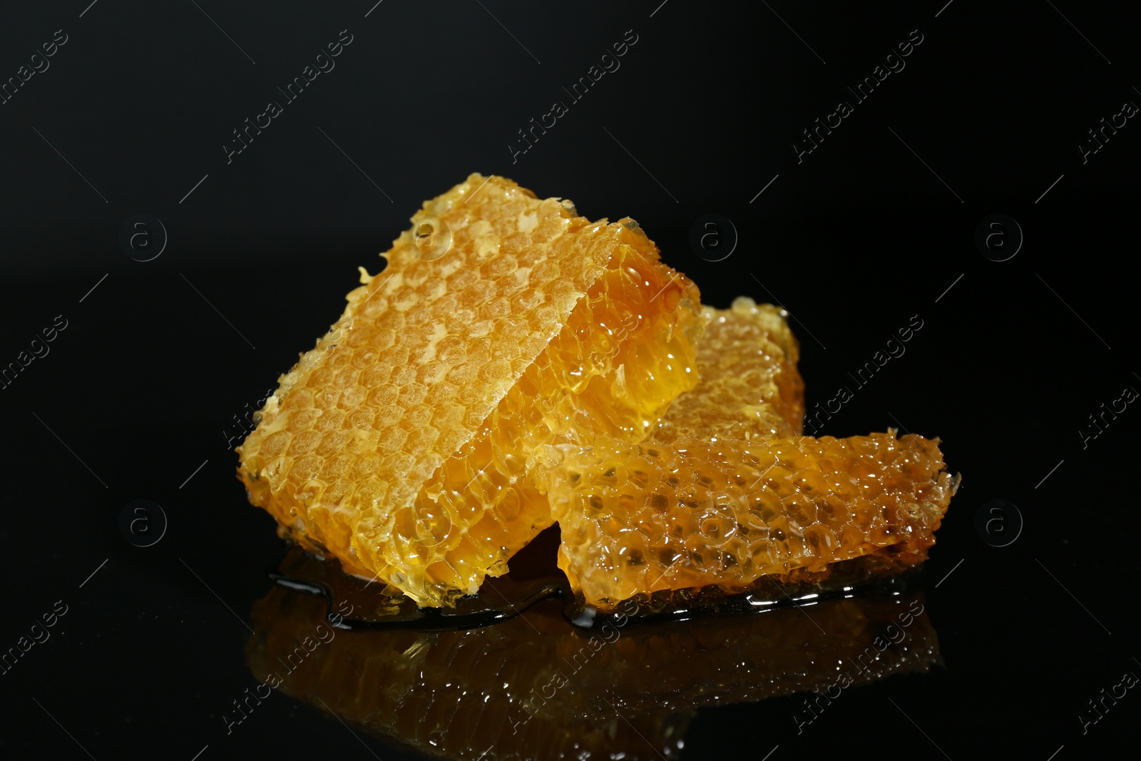 Photo of Natural honeycombs with tasty honey on black background