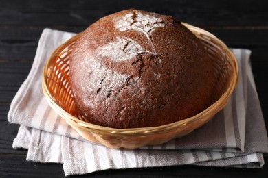 Photo of Wicker basket with fresh bread on black wooden table