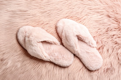 Photo of Pair of soft slippers on pink faux fur, flat lay