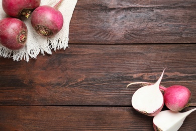 Photo of Red turnips on wooden table, flat lay. Space for text