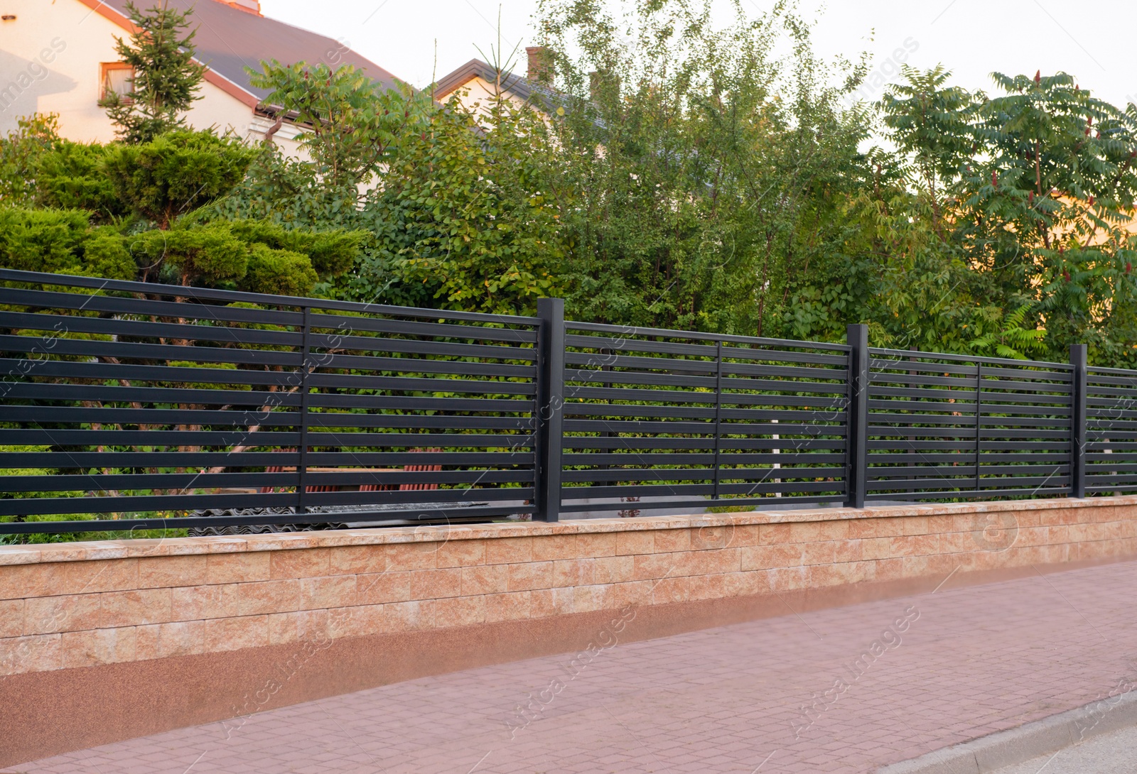 Photo of House and trees behind beautiful fence outdoors