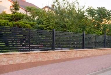 Photo of House and trees behind beautiful fence outdoors