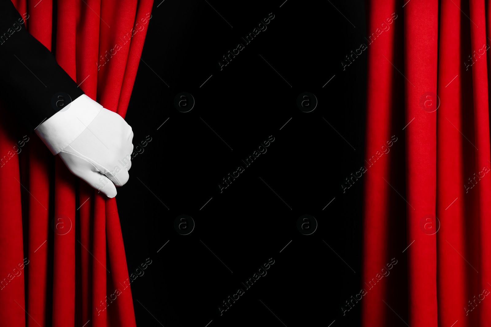 Photo of Person opening red front curtains on black background, closeup. Space for text