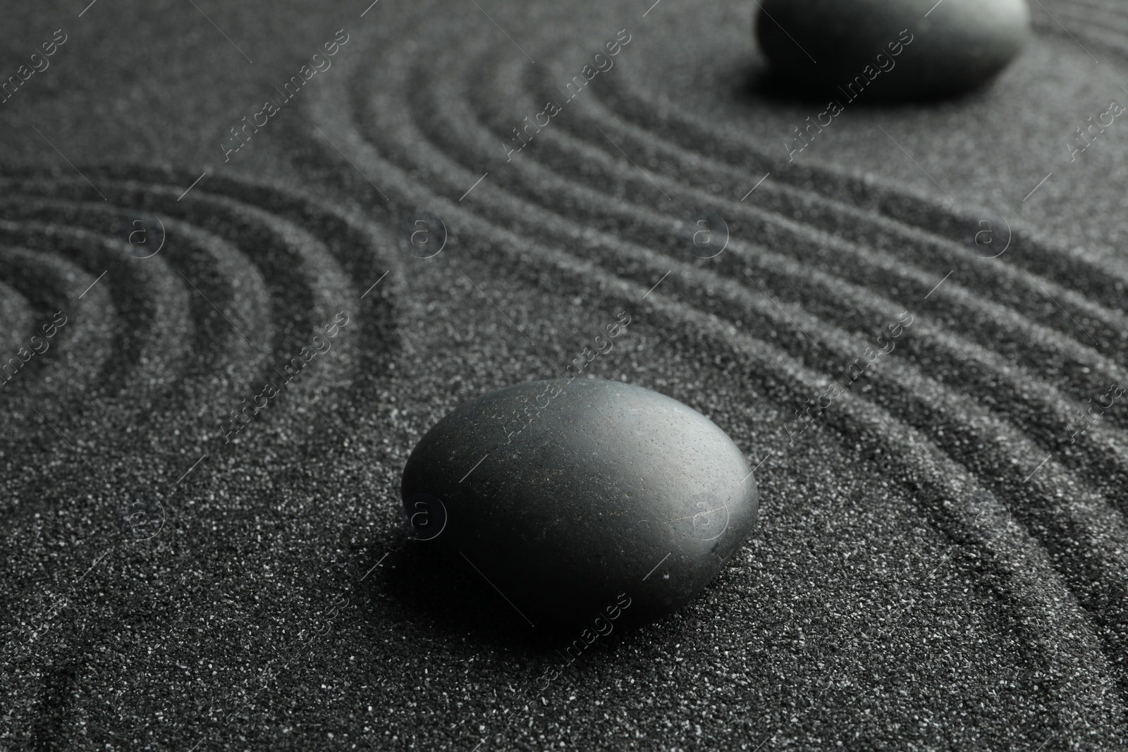 Photo of Black sand with stones and beautiful pattern. Zen concept