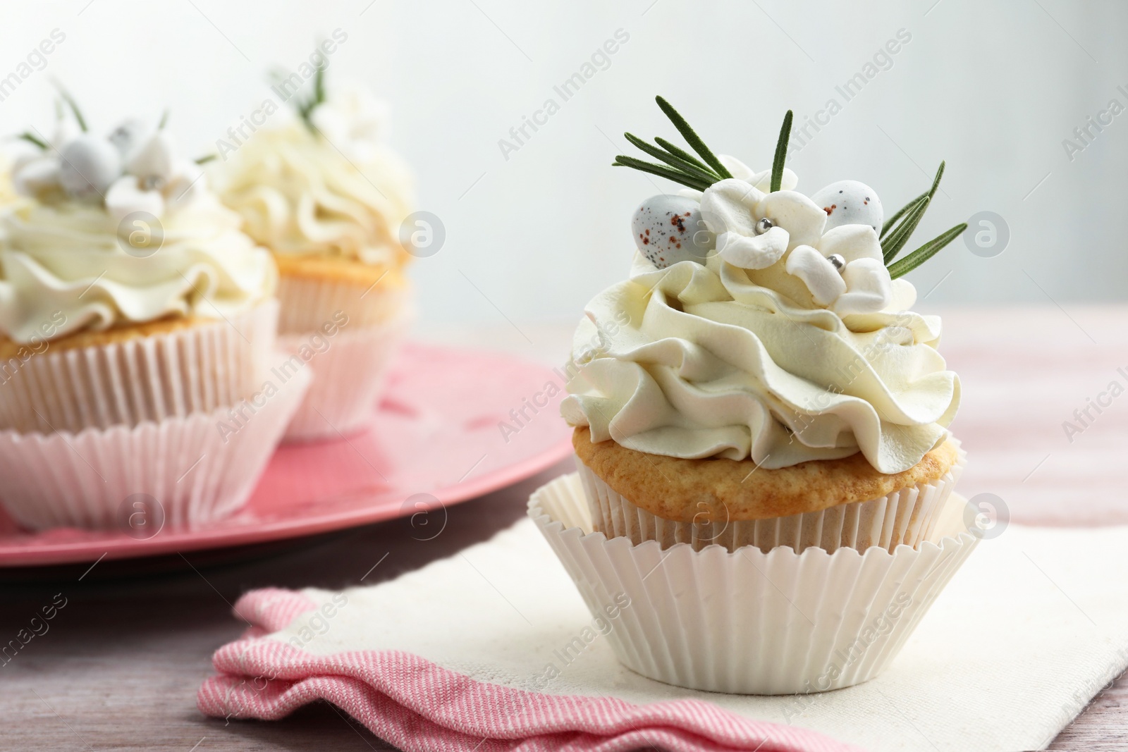 Photo of Tasty Easter cupcakes with vanilla cream on wooden table