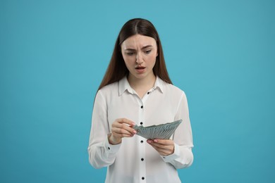 Woman with dollar banknotes on light blue background