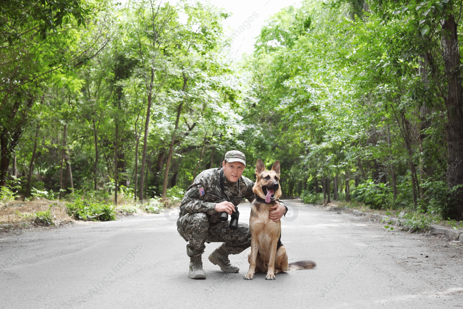 Photo of Man in military uniform with German shepherd dog, outdoors