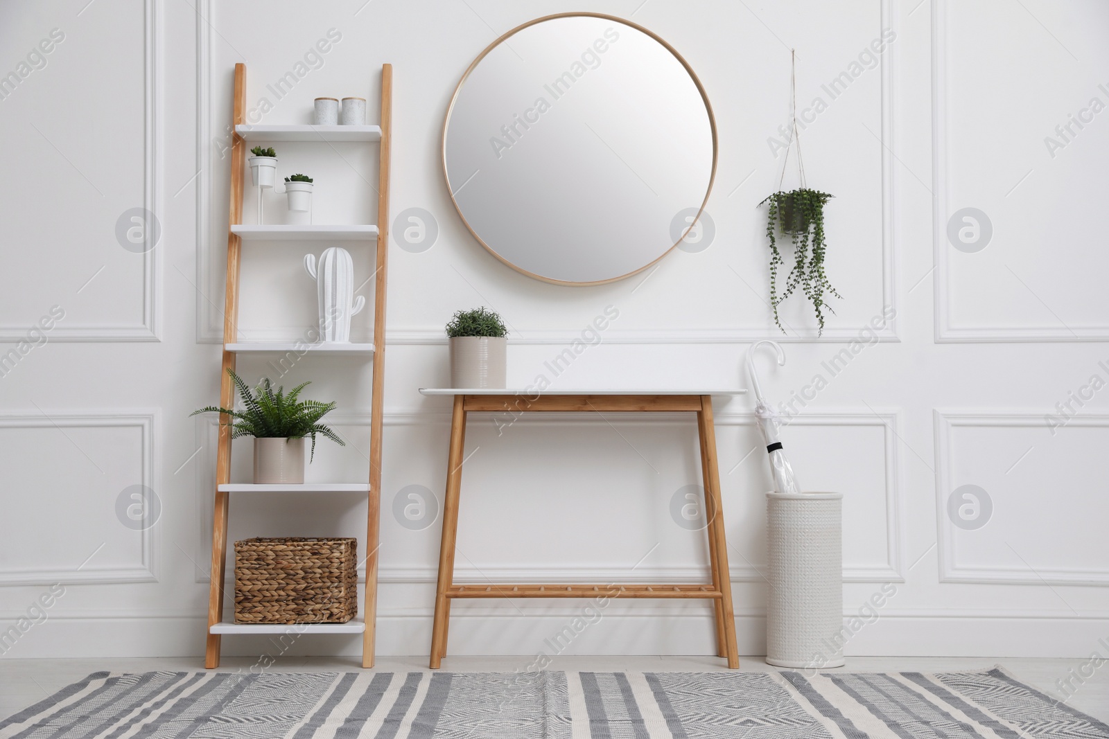 Photo of Console table with shelving unit and mirror on white wall in hallway. Interior design