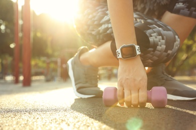 Photo of Woman wearing modern smart watch during training outdoors, closeup