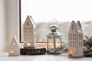 Beautiful house shaped candle holders and Christmas decor on windowsill indoors