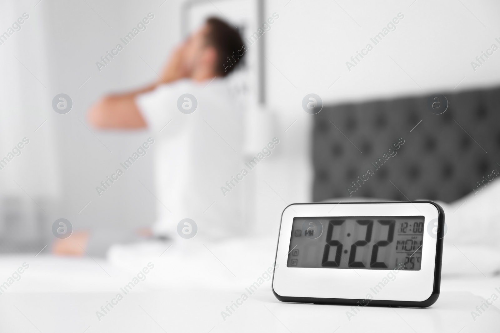 Photo of Digital alarm clock and blurred man on background. Time of day