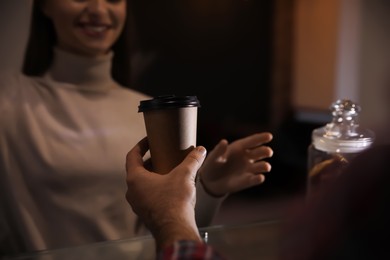 Photo of Barista giving takeaway coffee cup to client in cafe, closeup