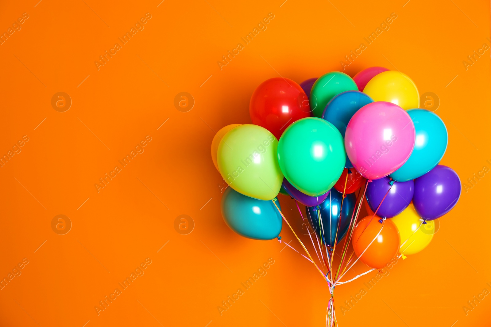 Photo of Bunch of bright balloons on color background with space for design