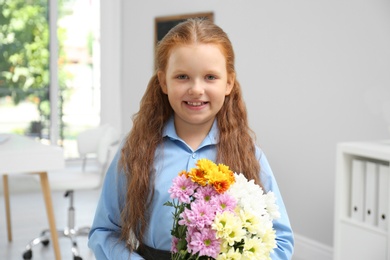 Photo of Happy schoolgirl with bouquet in classroom. Teacher's day