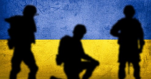 Image of Silhouettes of soldiers with Ukrainian flag colors on background. Military service during war