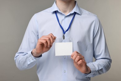 Photo of Man showing empty badge on grey background, closeup