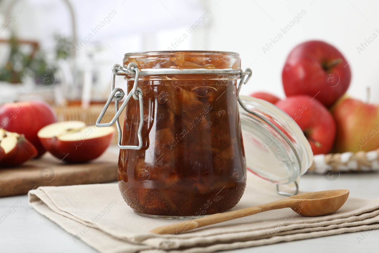 Photo of Delicious apple jam in jar and wooden spoon on table