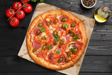 Photo of Delicious pizza Diablo and ingredients on black wooden table, flat lay