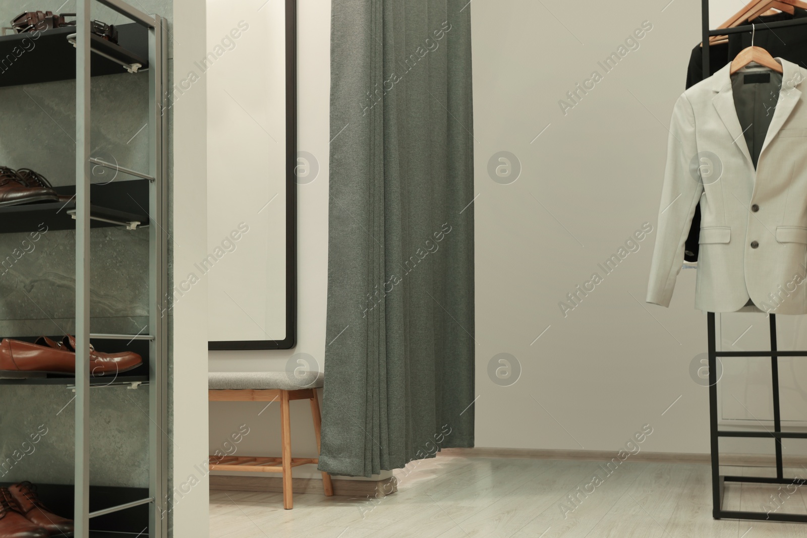 Photo of Dressing room with clothing rack in fashion store. Stylish design