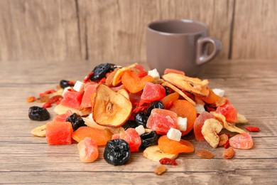 Pile of different tasty dried fruits on wooden table