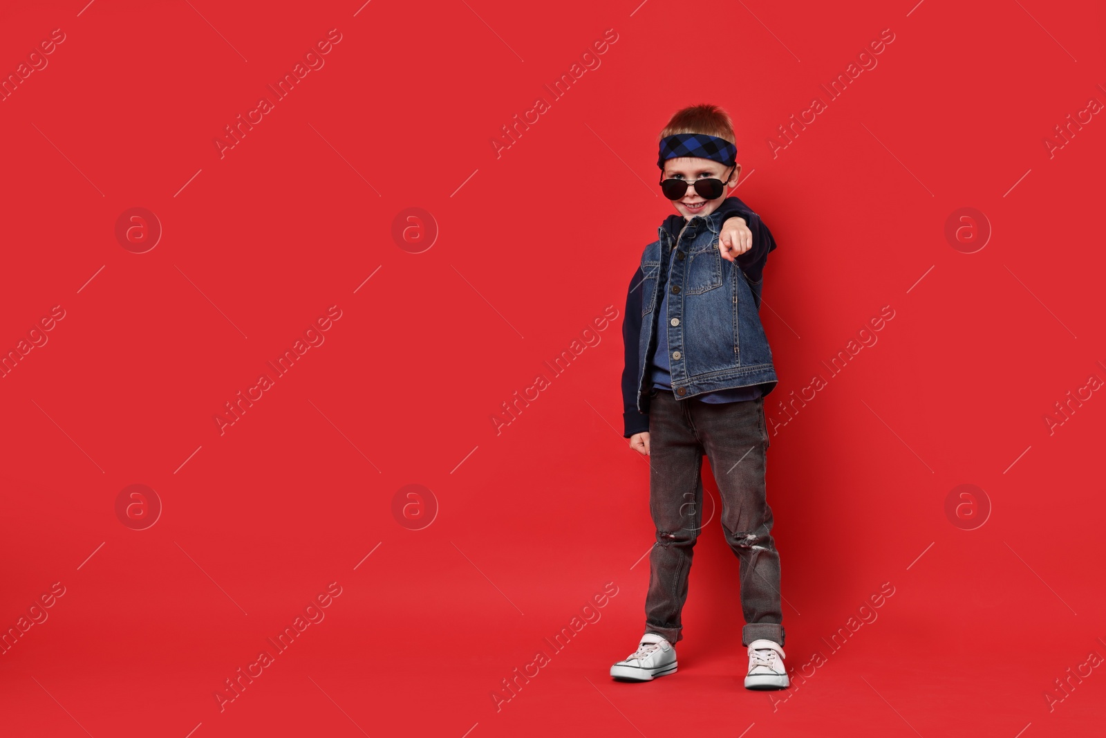 Photo of Happy little boy dancing on red background. Space for text