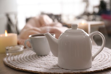 Photo of Teapot with cup of hot tea on table in room