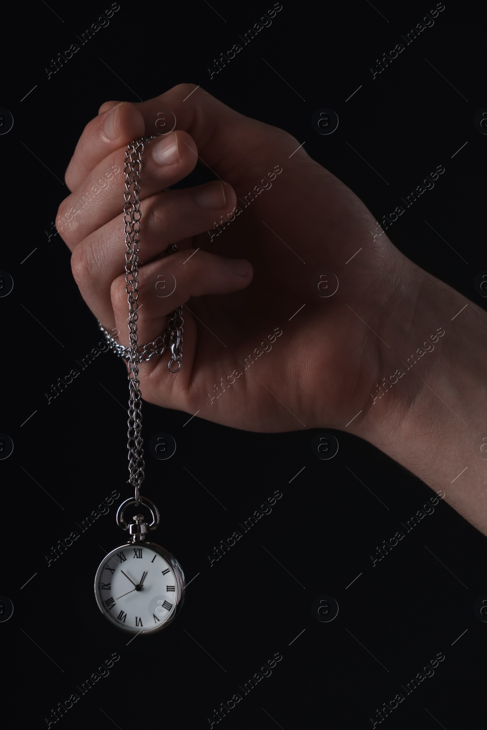 Photo of Man holding chain with elegant pocket watch on black background, closeup