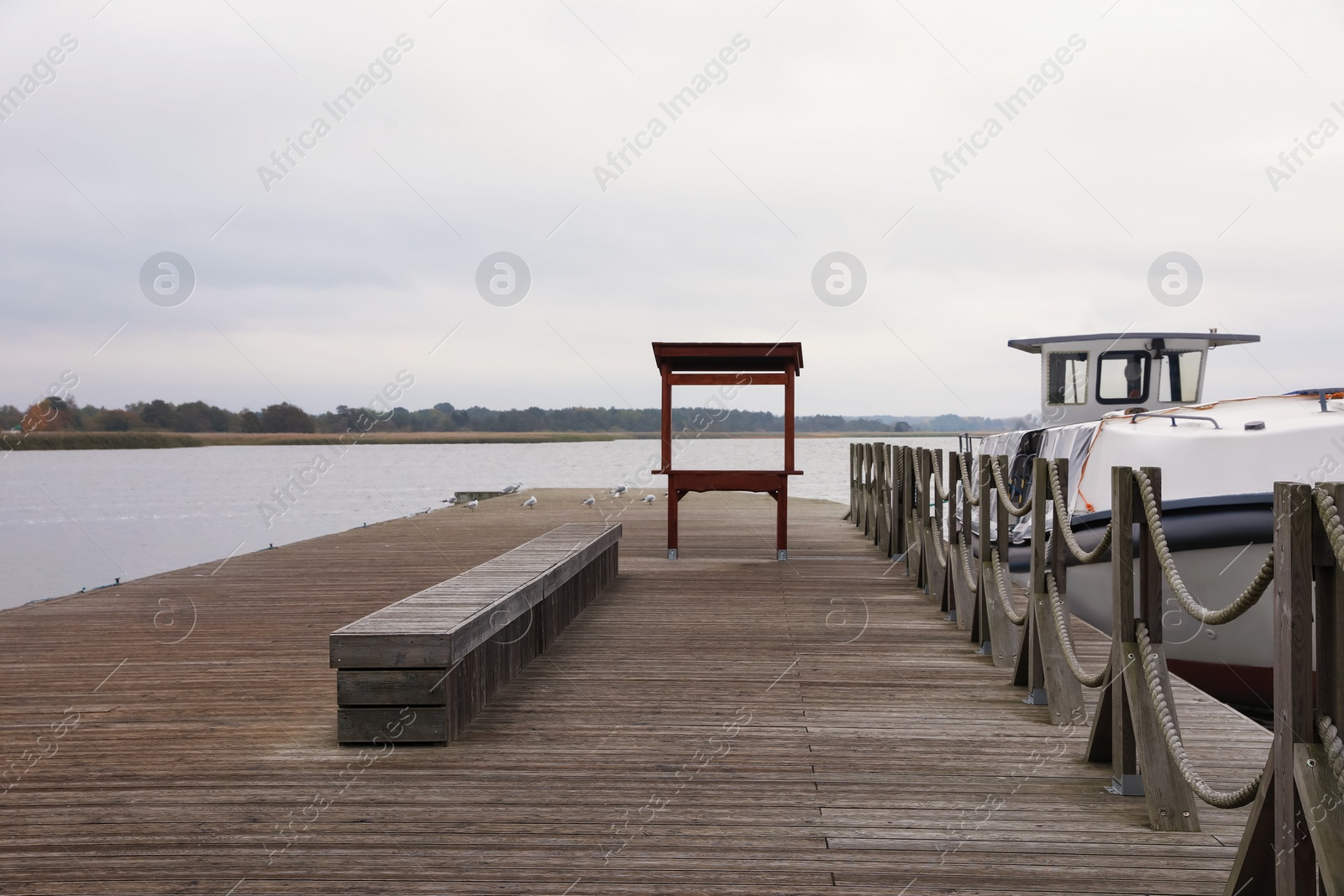 Photo of Wooden pier with moored boat near sea. Real estate