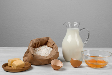 Photo of Raw eggs and other ingredients on white wooden table. Baking pie