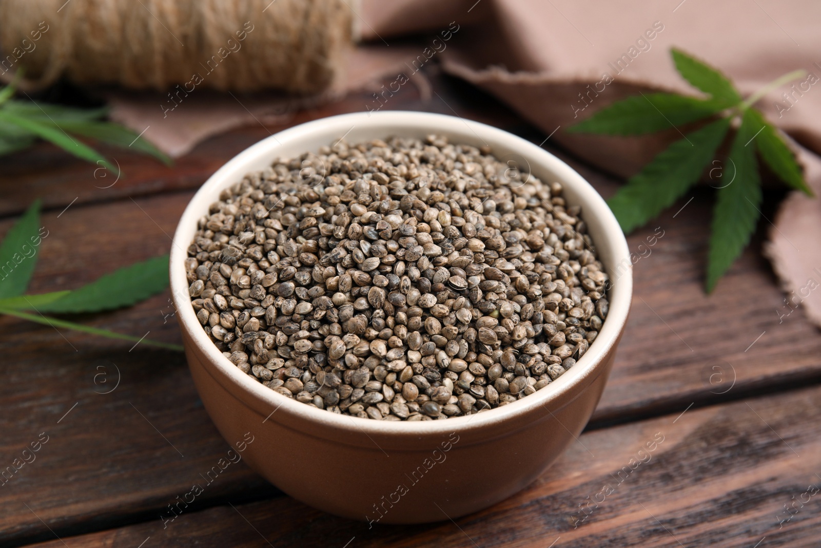 Photo of Bowl with hemp seeds on wooden table