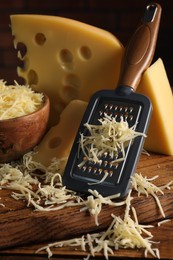 Grated, cut cheese and grater on wooden table, closeup