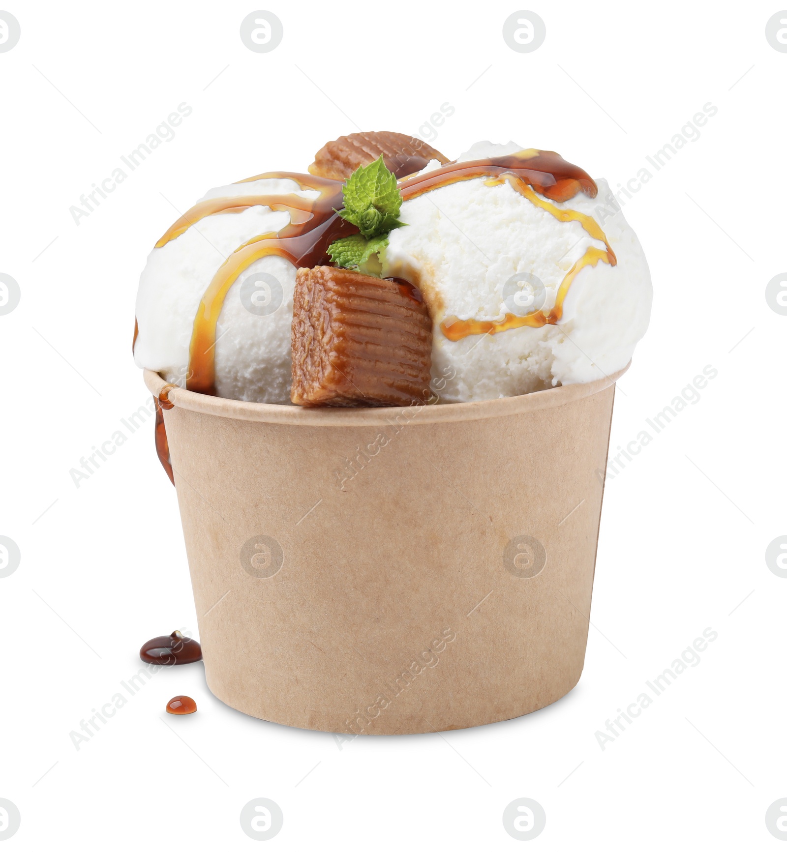 Photo of Scoops of tasty ice cream with mint leaves, caramel sauce and candies in paper cup isolated on white