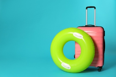Photo of Stylish suitcase and inflatable ring on color background. Space for text