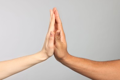 Photo of International relationships. People giving high five on light grey background, closeup