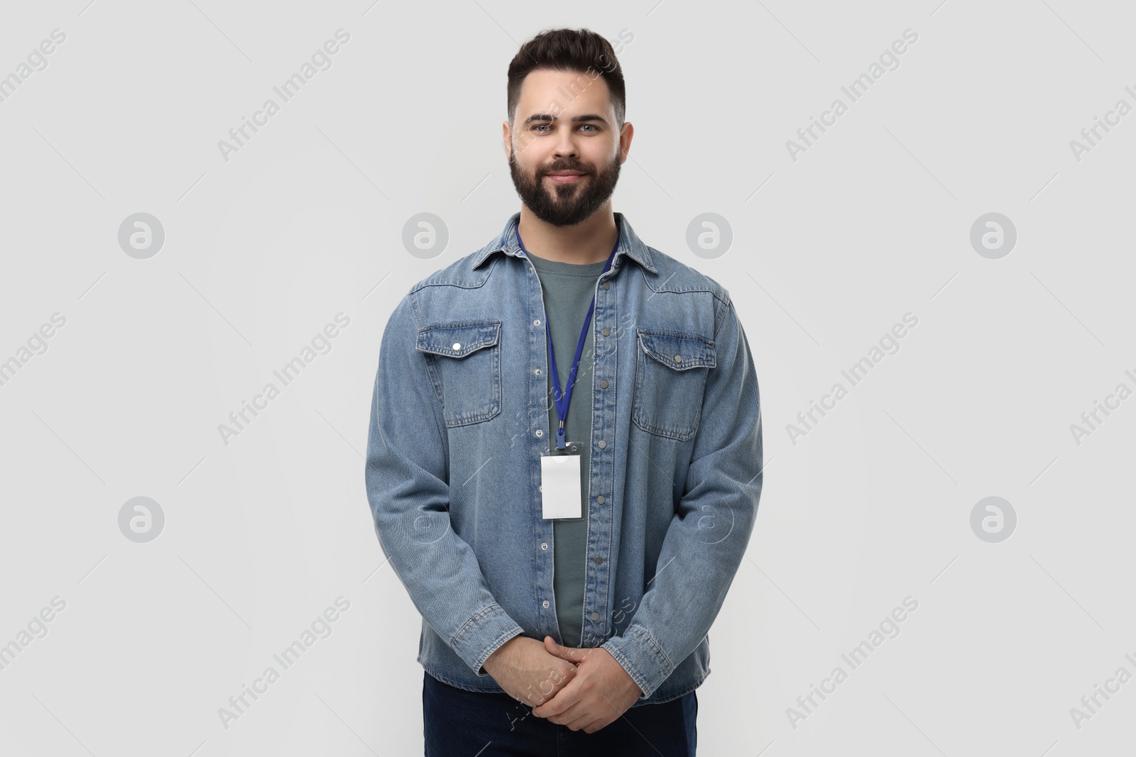 Photo of Handsome young man with blank badge on grey background