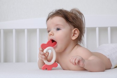 Cute little baby with teether in comfortable crib at home