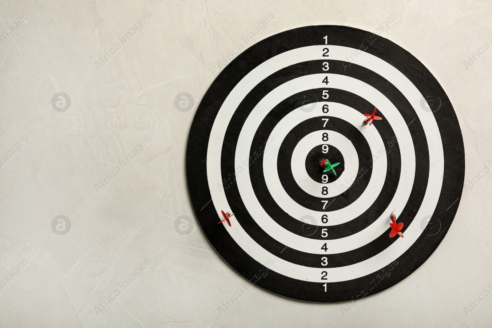 Photo of Dart board with color arrows on light stone background, top view. Space for text